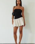 Colorblocked dress. Knit bodice. Woven skirt. Strapless elastic neckline. Inner rubber grip lining. Side hook and eyes and zipper closures. Unlined. drop waist dress. drop waist mini dress. strapless mini dress. strapless babydoll dress. summer dress. black and cream mini dress