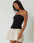 Colorblocked dress. Knit bodice. Woven skirt. Strapless elastic neckline. Inner rubber grip lining. Side hook and eyes and zipper closures. Unlined. drop waist dress. drop waist mini dress. strapless mini dress. strapless babydoll dress. summer dress. black and cream mini dress