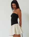 Colorblocked dress. Knit bodice. Woven skirt. Strapless elastic neckline. Inner rubber grip lining. Side hook and eyes and zipper closures. Unlined. drop waist dress. drop waist mini dress. strapless mini dress. strapless babydoll dress. summer dress. black and cream mini dress