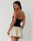 Colorblocked dress. Knit bodice. Woven skirt. Strapless elastic neckline. Inner rubber grip lining. Side hook and eyes and zipper closures. Unlined. drop waist dress. drop waist mini dress. strapless mini dress. strapless babydoll dress. summer dress. black and cream mini dress
