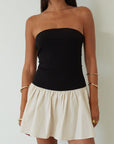 Colorblocked dress. Knit bodice. Woven skirt. Strapless elastic neckline. Inner rubber grip lining. Side hook and eyes and zipper closures. Unlined. drop waist dress. drop waist mini dress. strapless mini dress. strapless babydoll dress. summer dress. black and cream mini dress