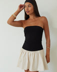 Colorblocked dress. Knit bodice. Woven skirt. Strapless elastic neckline. Inner rubber grip lining. Side hook and eyes and zipper closures. Unlined. drop waist dress. drop waist mini dress. strapless mini dress. strapless babydoll dress. summer dress. black and cream mini dress