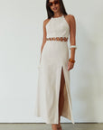 Woven maxi dress. Adjustable halter tie neckline. Back hook and eye and zipper closures. Ring waist details. Front slit. Fully lined. tan maxi dress. beige maxi dress. summer vacation dress.