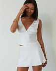 Satin sleeveless crop top. Fixed straps. Front flower detail. Side zipper closure. Back tie closure. Partially lined. white satin tank top. satin tank top. summer top