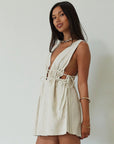 Woven sleeveless dress. Fixed straps. Adjustable drawstring waist. Unlined. tan mini dress. cream mini dress. summer dress. dinner dress. evening dress. vacation dress. vacation outfit