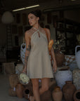 Woven dress. Adjustable halter neckline with tie closure. Back hook and eye and zipper closures. Fully lined. European summer. European summer dress. European summer aesthetic. Tuscany outfit inso. Tuscany aesthetic. Summer dress. oat mini dress. beige mini dress. tan mini dress. mini halter neck dress. summer outfit. everyday dress. vacation dress. outfit to wear to tuscany. nice dinner dress. dinner dress. day dress.