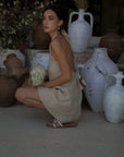 Woven dress. Adjustable halter neckline with tie closure. Back hook and eye and zipper closures. Fully lined. European summer. European summer dress. European summer aesthetic. Tuscany outfit inso. Tuscany aesthetic. Summer dress. oat mini dress. beige mini dress. tan mini dress. mini halter neck dress. summer outfit. everyday dress. vacation dress. outfit to wear to tuscany. nice dinner dress. dinner dress. day dress.