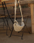Woven macrame crossbody bag. Fixed strap. Fringe trim. Front zipper closure. Fully lined.