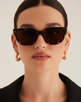 Person wearing tortoiseshell sunglasses with a neutral background
Tort cat eye sunglasses