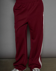 Woven burgundy track pants. Elastic waistband. Side pockets. Side stripes. Unlined. street fashion. trendy track pants