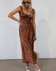 brown and white Polka dot printed satin maxi dress. Fixed straps. Lace trimmed neckline. Front drawstring closure. Side hook and eye and zipper closures. Back tie closure. Elastic back. Fully lined. fall dress. fall wedding guest dress. fall outfit