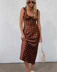 brown and white Polka dot printed satin maxi dress. Fixed straps. Lace trimmed neckline. Front drawstring closure. Side hook and eye and zipper closures. Back tie closure. Elastic back. Fully lined. fall dress. fall wedding guest dress. fall outfit