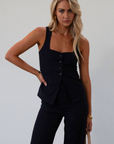 Plaid woven sleeveless top. Front button down closure. Faux front pockets. Adjustable back tie closure. Fully lined. navy blue blouse. work outfit. business casual outfit.