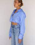 Striped woven cropped shirt. Collar neckline. Long sleeves with button closures. Front button down closures. Drawstring side ties. Unlined. blue stripe crop top. studious oufit