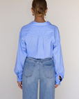 Striped woven cropped shirt. Collar neckline. Long sleeves with button closures. Front button down closures. Drawstring side ties. Unlined. blue stripe crop top. studious oufit