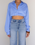 Striped woven cropped shirt. Collar neckline. Long sleeves with button closures. Front button down closures. Drawstring side ties. Unlined. blue stripe crop top. studious oufit