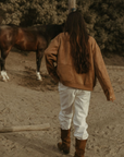 Tan brown faux suede jacket. Front zipper closure. Front and side pockets. Long sleeves with button closures. Fully lined. suede bomber jacket