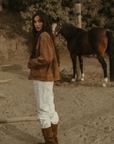 Tan brown faux suede jacket. Front zipper closure. Front and side pockets. Long sleeves with button closures. Fully lined. suede bomber jacket