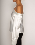 white Satin top. Folded off the shoulder neckline. Long sleeves with button closures. Unlined. white satin one shoulder top.