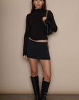 Knit skirt. Open sides with gold metal ring details. Shorts lining. Back hook and eye and zipper closures. black mini skirt