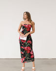 Floral printed knit mesh dress. Elastic strapless neckline. Inner rubber grip lining. Back slit. Black dress with large red floral.