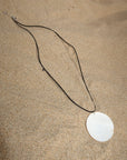 Cord necklace. Large round shell pendant. Adjustable lobster clasp closure.