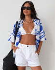 Printed woven shirt. Collar neckline. Short sleeves. Front button down closure. Unlined. cover up shirt. button up cover up. blue and white printed shirt. summer top. beach cover up. pool coverup