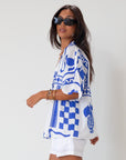 Printed woven shirt. Collar neckline. Short sleeves. Front button down closure. Unlined. cover up shirt. button up cover up. blue and white printed shirt. summer top. beach cover up. pool coverup