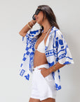 Printed woven shirt. Collar neckline. Short sleeves. Front button down closure. Unlined. cover up shirt. button up cover up. blue and white printed shirt. summer top. beach cover up. pool coverup