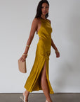 Satin maxi dress. Adjustable halter tie neckline. Side hook and eye and zipper closures. Front slit. Back tie closure. Partially lined. gold dress. gold midi dress. guest wedding dress. fall wedding.