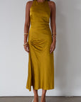 Satin maxi dress. Adjustable halter tie neckline. Side hook and eye and zipper closures. Front slit. Back tie closure. Partially lined. gold dress. gold midi dress. guest wedding dress. fall wedding.