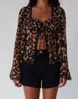 Animal printed chiffon top. Long sleeves with elastic openings. Underwire cups. Front lace up closures. Lace trim. Partially lined. leopard top. cheetah top. going out top. summer top