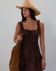 Smocked woven dress. Elastic straps. Front tie closure. Elastic waist. Side pockets. Fully lined. brown mini dress. fall transition dress