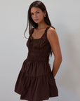 Smocked woven dress. Elastic straps. Front tie closure. Elastic waist. Side pockets. Fully lined. brown mini dress. fall transition dress