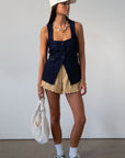Denim sleeveless top. Fixed straps. Front button down closures. Faux front pockets. Adjustable back tie closure. Unlined. denim vest