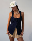 Denim sleeveless top. Fixed straps. Front button down closures. Faux front pockets. Adjustable back tie closure. Unlined. denim vest