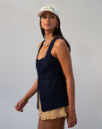 Denim sleeveless top. Fixed straps. Front button down closures. Faux front pockets. Adjustable back tie closure. Unlined. denim vest