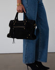 black Suede bag. Adjustable/detachable strap. Fixed top handles. Top zipper closure. Front zipper pocket. Fully lined. Inner pockets and zipper pocket.
