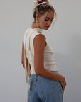 Ribbed knit sleeveless top. V-neckline. Front button down closure. Unlined. Neck tie. white top. white knit vest. fall outfit. fall top. fall transition top.