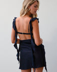 Satin dress. Adjustable straps with ruffle trim. Side hook and eye and zipper closures. Elastic back strap with clasp closure. Fully lined. navy blue mini dress. holiday dress. mini holiday dress