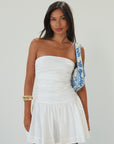 Woven mini dress. Strapless neckline. Inner rubber grip lining. Ruched bodice. Back hook and eye and zipper closure. Fully lined. white mini dress. white strapless mini dress. bridal shower dress. bridal dress. engagement dress. bride outfit. summer dress. fancy dinner dress