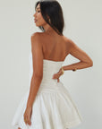 Woven mini dress. Strapless neckline. Inner rubber grip lining. Ruched bodice. Back hook and eye and zipper closure. Fully lined. white mini dress. white strapless mini dress. bridal shower dress. bridal dress. engagement dress. bride outfit. summer dress. fancy dinner dress
