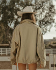 Denim jacket. Collar neckline. Long sleeves. Front zipper closure. Front pockets. Elastic sides. Fully lined. barn jacket. beige barn jacket. ranch shoot