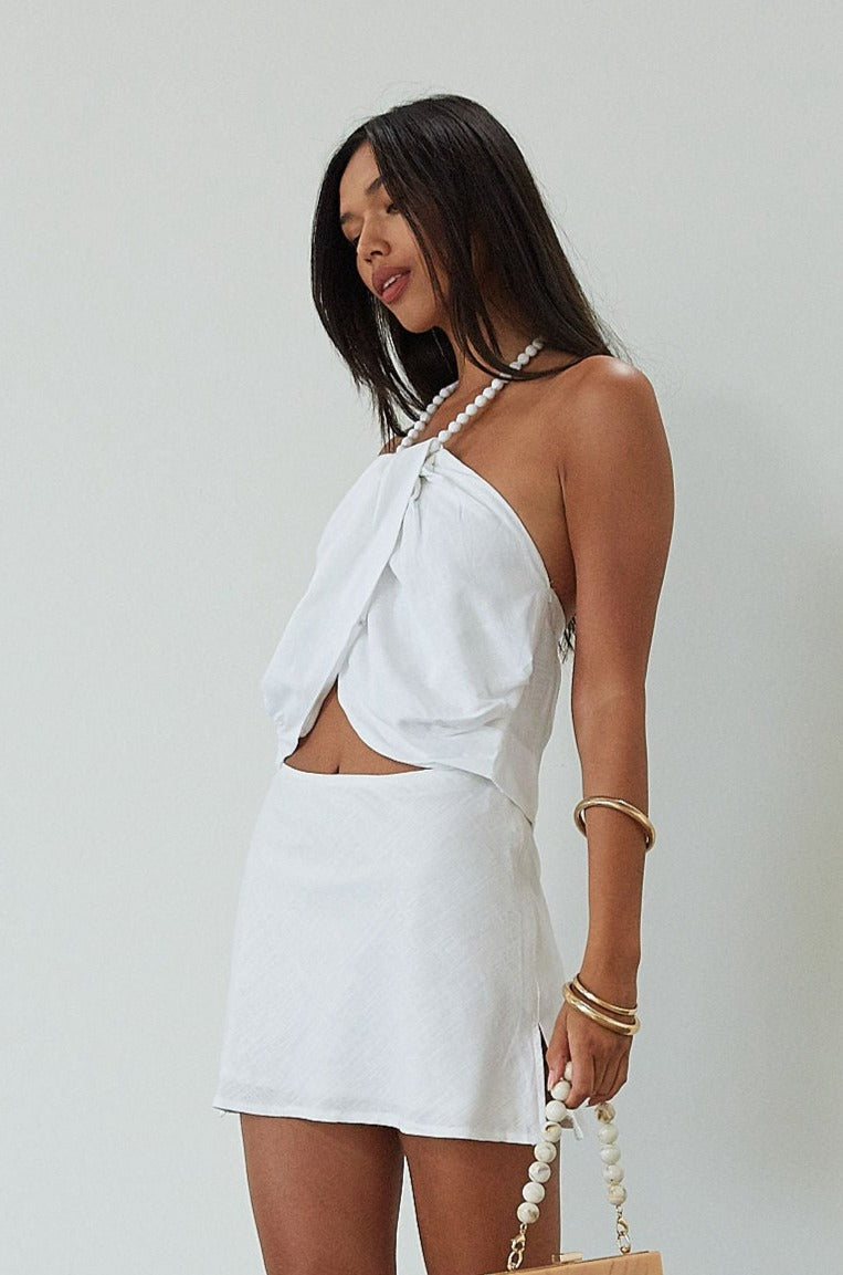 Woven crop top. Beaded halter neckline with adjustable tie closure. Front snap closure. Unlined. white cropped tank top. white halter top. asymmetrical top. summer top. vacation top. vacation outfit