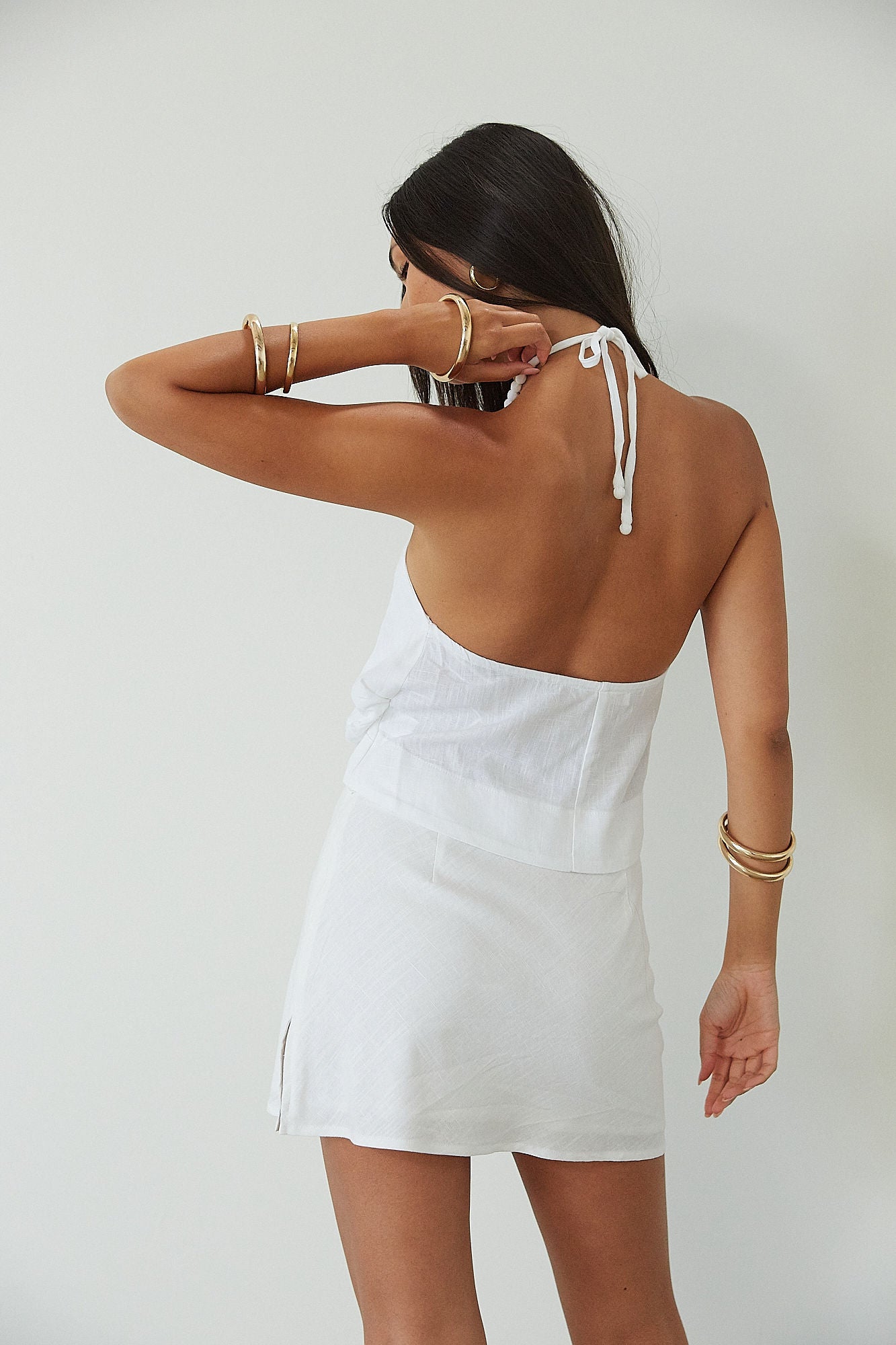 Woven crop top. Beaded halter neckline with adjustable tie closure. Front snap closure. Unlined. white cropped tank top. white halter top. asymmetrical top. summer top. vacation top. vacation outfit