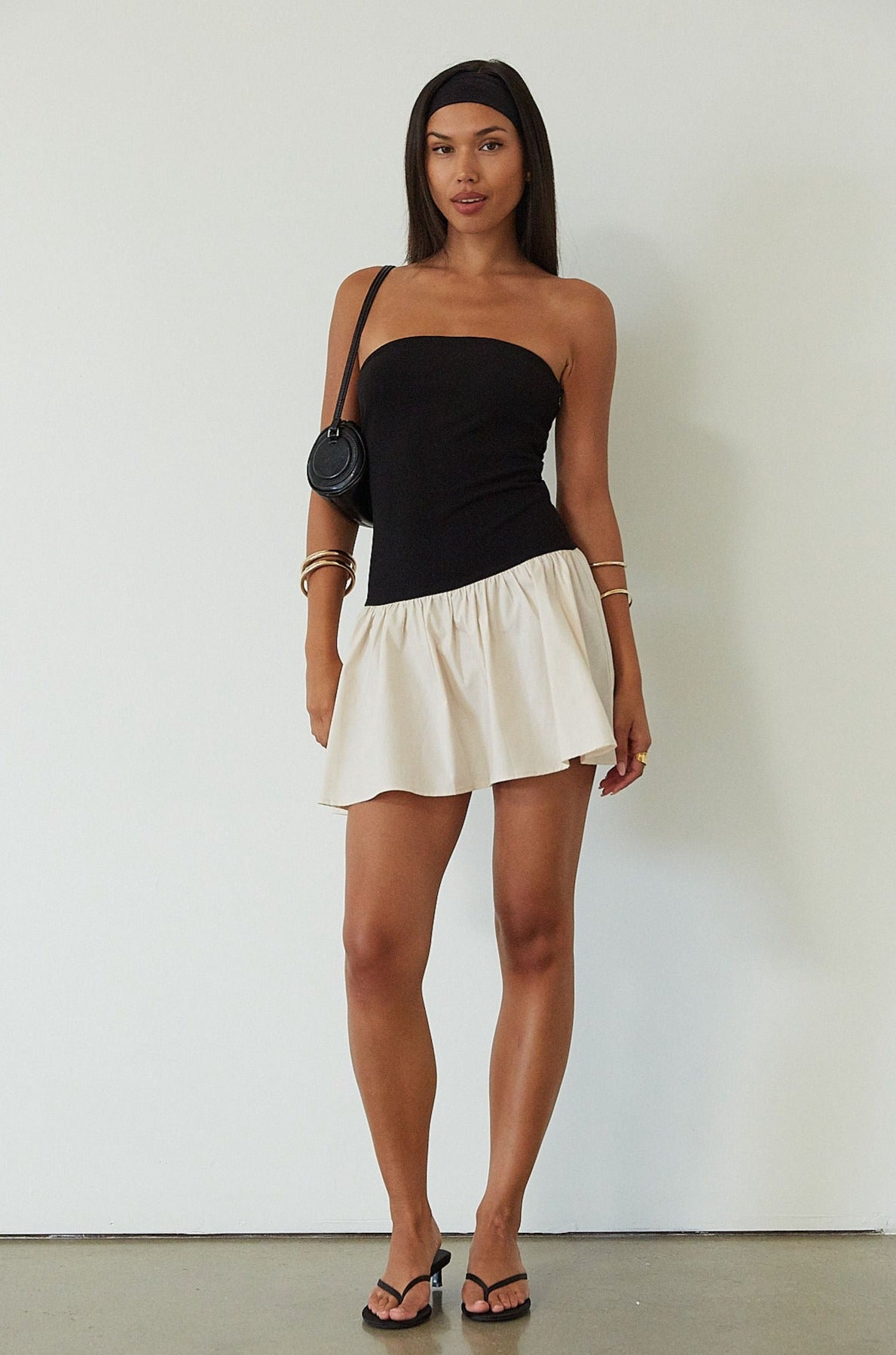 Colorblocked dress. Knit bodice. Woven skirt. Strapless elastic neckline. Inner rubber grip lining. Side hook and eyes and zipper closures. Unlined. drop waist dress. drop waist mini dress. strapless mini dress. strapless babydoll dress. summer dress. black and cream mini dress