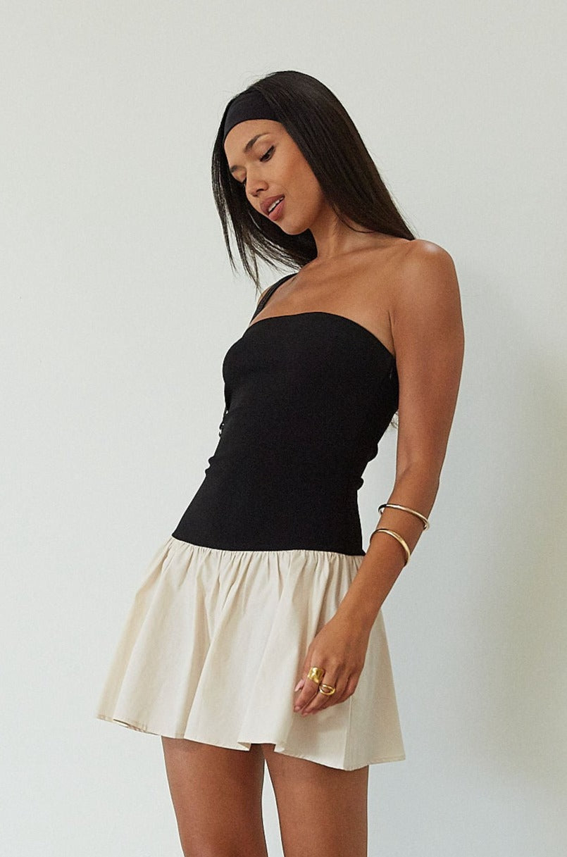 Colorblocked dress. Knit bodice. Woven skirt. Strapless elastic neckline. Inner rubber grip lining. Side hook and eyes and zipper closures. Unlined. drop waist dress. drop waist mini dress. strapless mini dress. strapless babydoll dress. summer dress. black and cream mini dress
