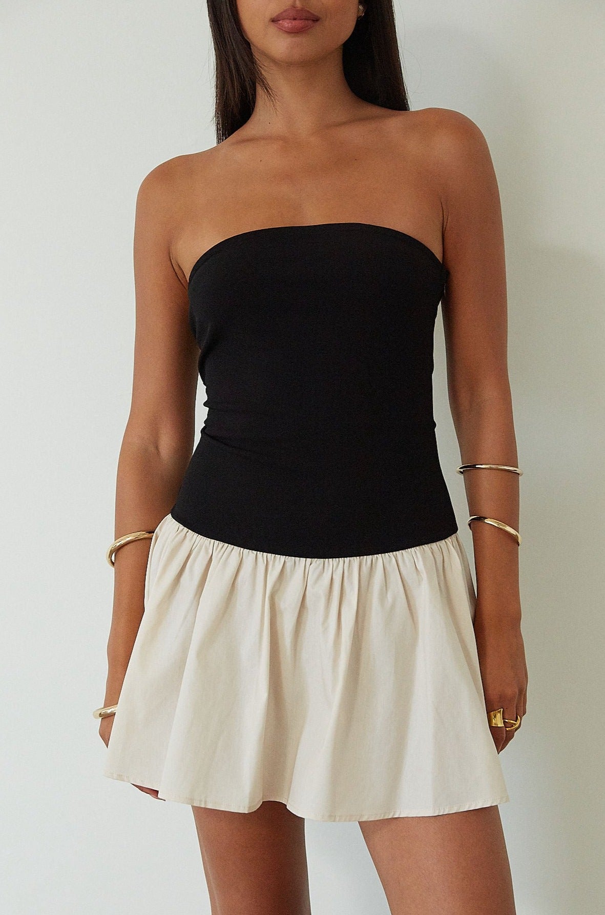 Colorblocked dress. Knit bodice. Woven skirt. Strapless elastic neckline. Inner rubber grip lining. Side hook and eyes and zipper closures. Unlined. drop waist dress. drop waist mini dress. strapless mini dress. strapless babydoll dress. summer dress. black and cream mini dress
