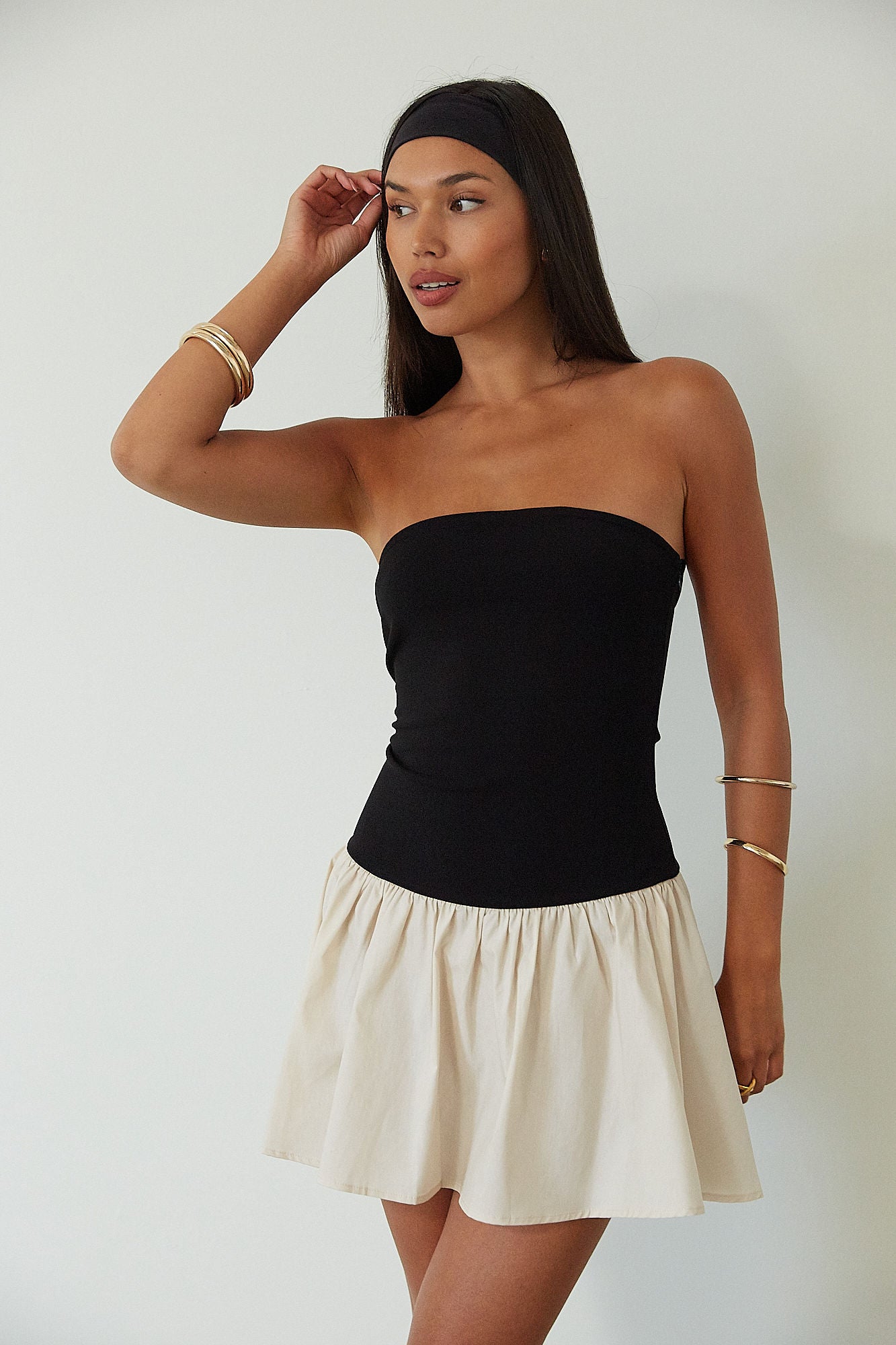 Colorblocked dress. Knit bodice. Woven skirt. Strapless elastic neckline. Inner rubber grip lining. Side hook and eyes and zipper closures. Unlined. drop waist dress. drop waist mini dress. strapless mini dress. strapless babydoll dress. summer dress. black and cream mini dress