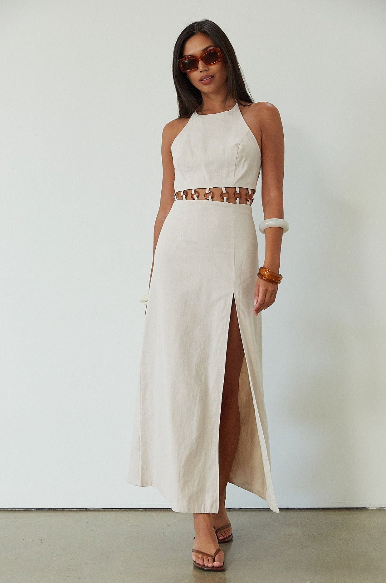 Woven maxi dress. Adjustable halter tie neckline. Back hook and eye and zipper closures. Ring waist details. Front slit. Fully lined. tan maxi dress. beige maxi dress. summer vacation dress. 